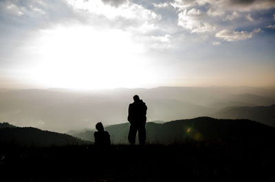 Silhouette people on mountain against sky during sunset