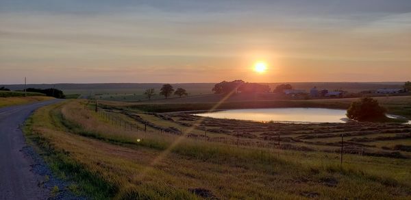 Scenic view of agricultural field against sky during sunset