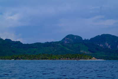 Scenic view of sea by mountains against sky