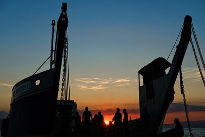 Silhouette people at construction site against sky during sunset