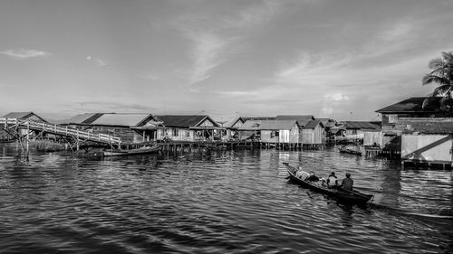 People in boat on river against sky