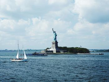 Statue of liberty amidst sea against cloudy sky