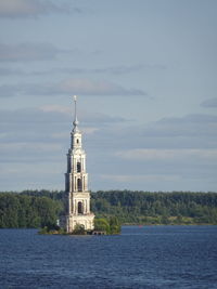 Lighthouse by sea against sky