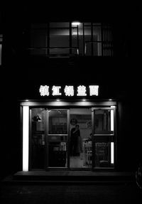 Rear view of woman standing by window at night