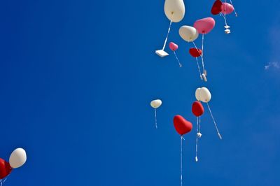 Low angle view of balloons against blue sky