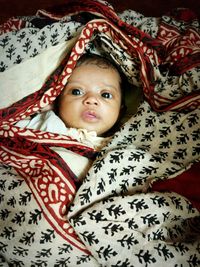 High angle view of cute baby girl lying on patterned sari