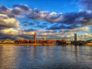 River by factory against sky during sunset