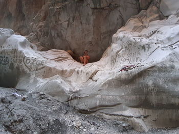 Rear view of woman sitting on rock