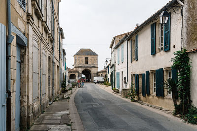 Empty road amidst buildings in city