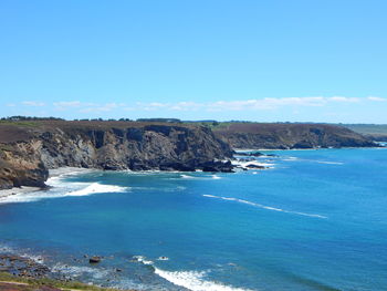 Scenic view of cliff by sea against sky