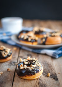 Close-up of chocolate glazed donuts with hazelnuts on wooden background