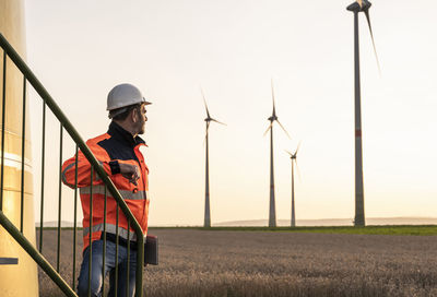 Male inspector at wind turbines during sunset