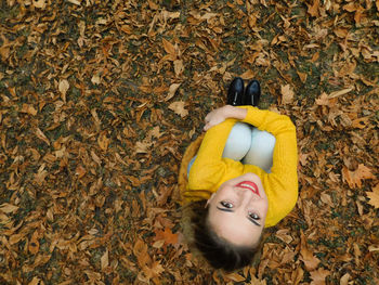 High angle portrait of woman lying down on autumn leaves