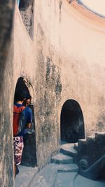 Rear view of woman standing against wall