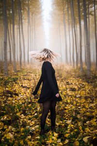 Full length of woman standing amidst leaves in forest