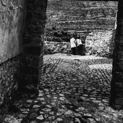 Rear view of people standing on stone wall