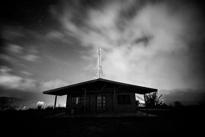 Low angle view of house on silhouette field against sky