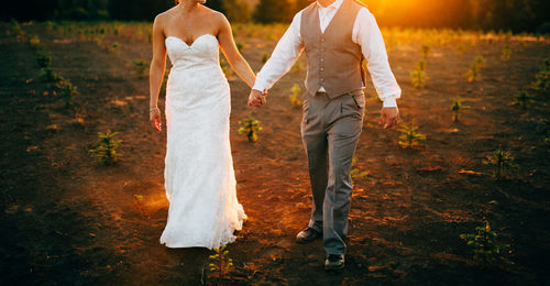 Low section of couple walking on land during sunset
