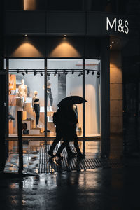 Man and woman walking on illuminated road in city