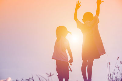 Low angle view of women standing against sky during sunset