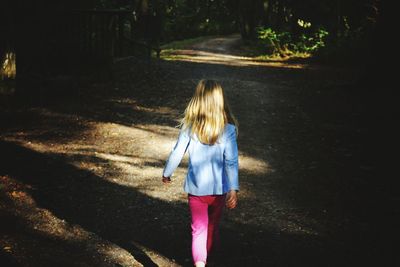 Rear view of girl walking on road