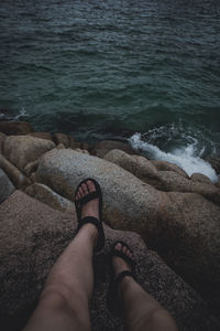 Low section of woman on rock at beach