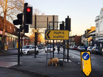 Road sign in city against sky