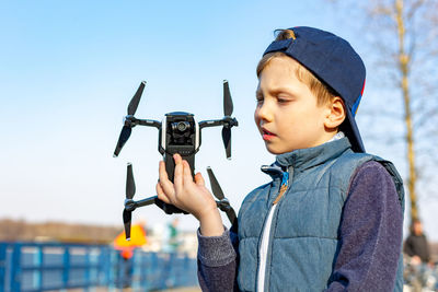 Full length of boy photographing with mobile phone against sky