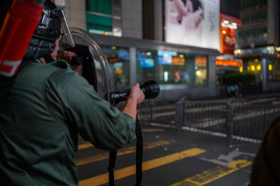 Rear view of man standing on illuminated street at night