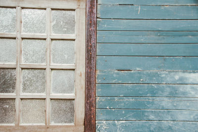 Closed window by weathered blue wooden wall