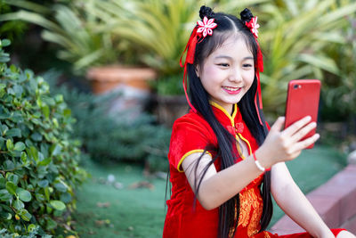 Cute girl doing selfie while sitting against plants