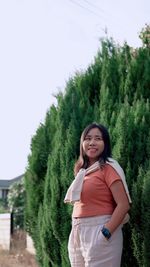 Portrait of young woman standing against trees