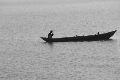 Silhouette people on boat in sea against sky