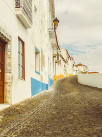 Narrow alley amidst houses and buildings against sky