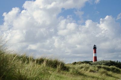 Lighthouse on field against sky