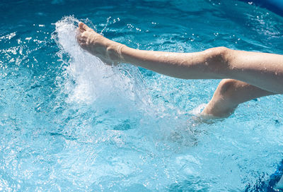 Low section of man splashing in swimming pool