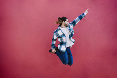 Full length of a young woman jumping against wall