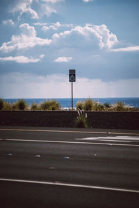 Road sign by street against sky