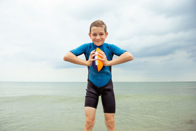 Portrait of boy standing at shore against sky