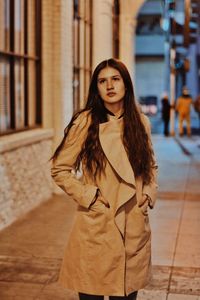 Beautiful woman wearing overcoat on footpath at night