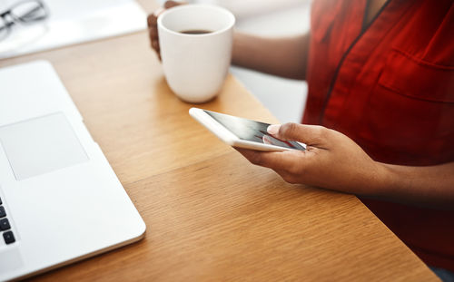 Midsection of woman using mobile phone on table