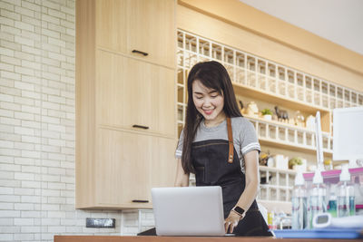 Young woman using phone while standing at home