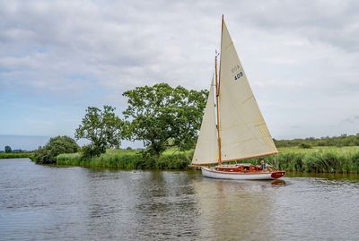 Sailboat sailing on lake against sky