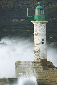 Lighthouse by sea against building