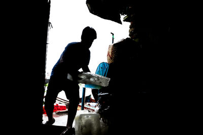 Silhouette man with arms raised standing against sky