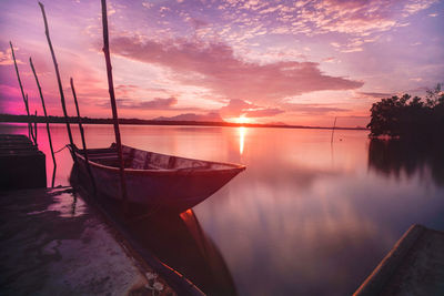 Sailboats moored on sea against sky during sunset