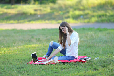 Young woman using laptop while sitting at park