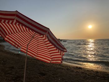 Lifeguard hut on beach against sky during sunset