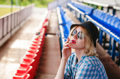 Woman smoking cigarette in stadium