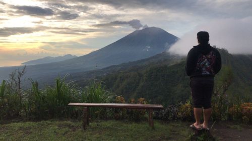 Rear view of man looking at mountains against sky